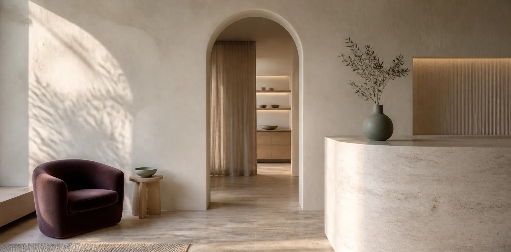 Warm, minimal skin studio interior with limewash walls and a plum chair