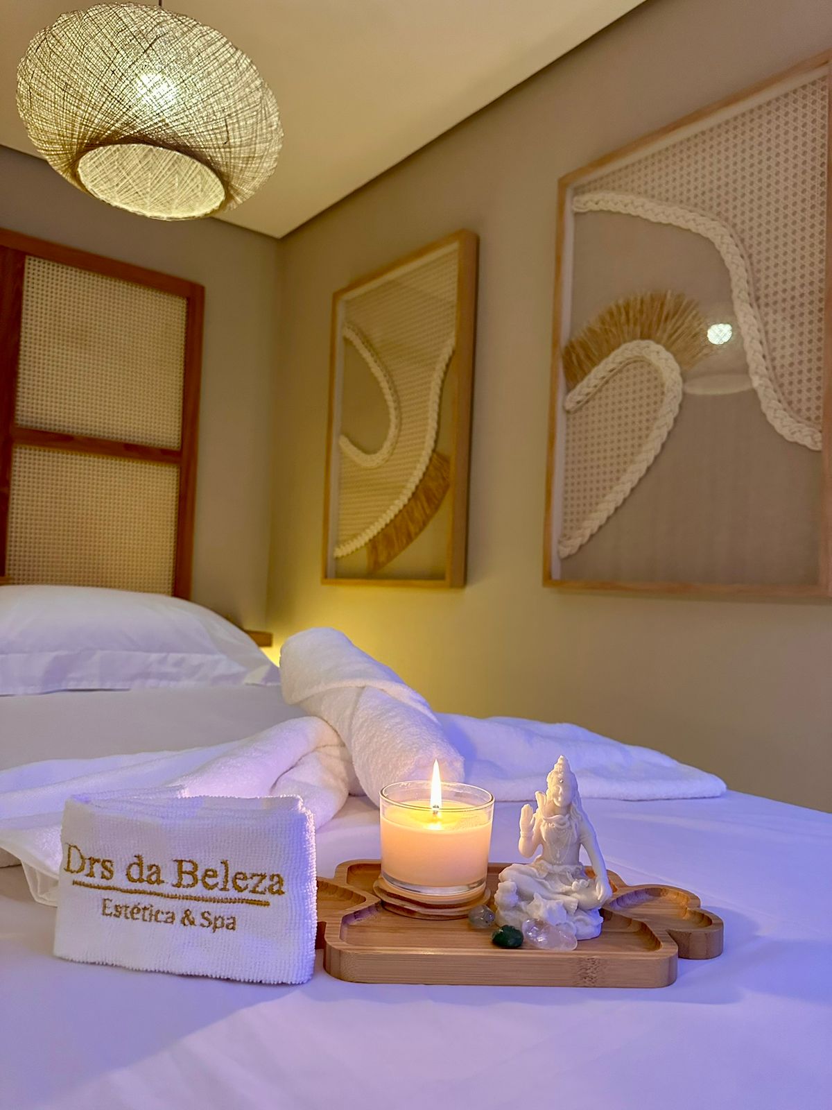 Drs da Beleza spa treatment room with a candle, towels, and massage table